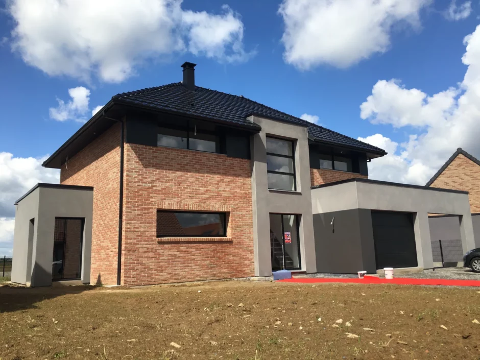 Façade de la maison construite : briques, enduit gris et toiture 4 pans